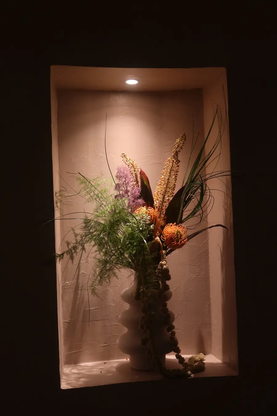 Arreglo floral en una hornacina iluminada de Santoku Barrio